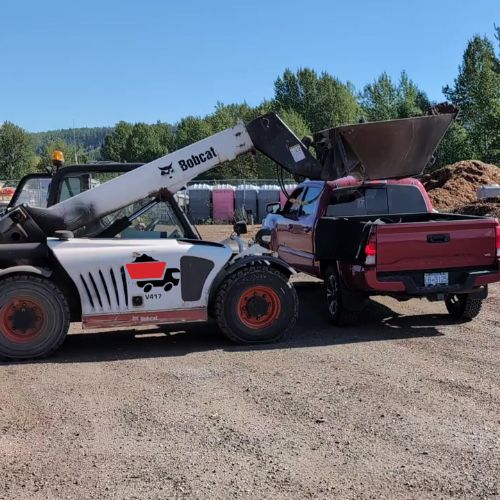 The one-yard bucket loading a pickup from above, clear of the truck’s sides